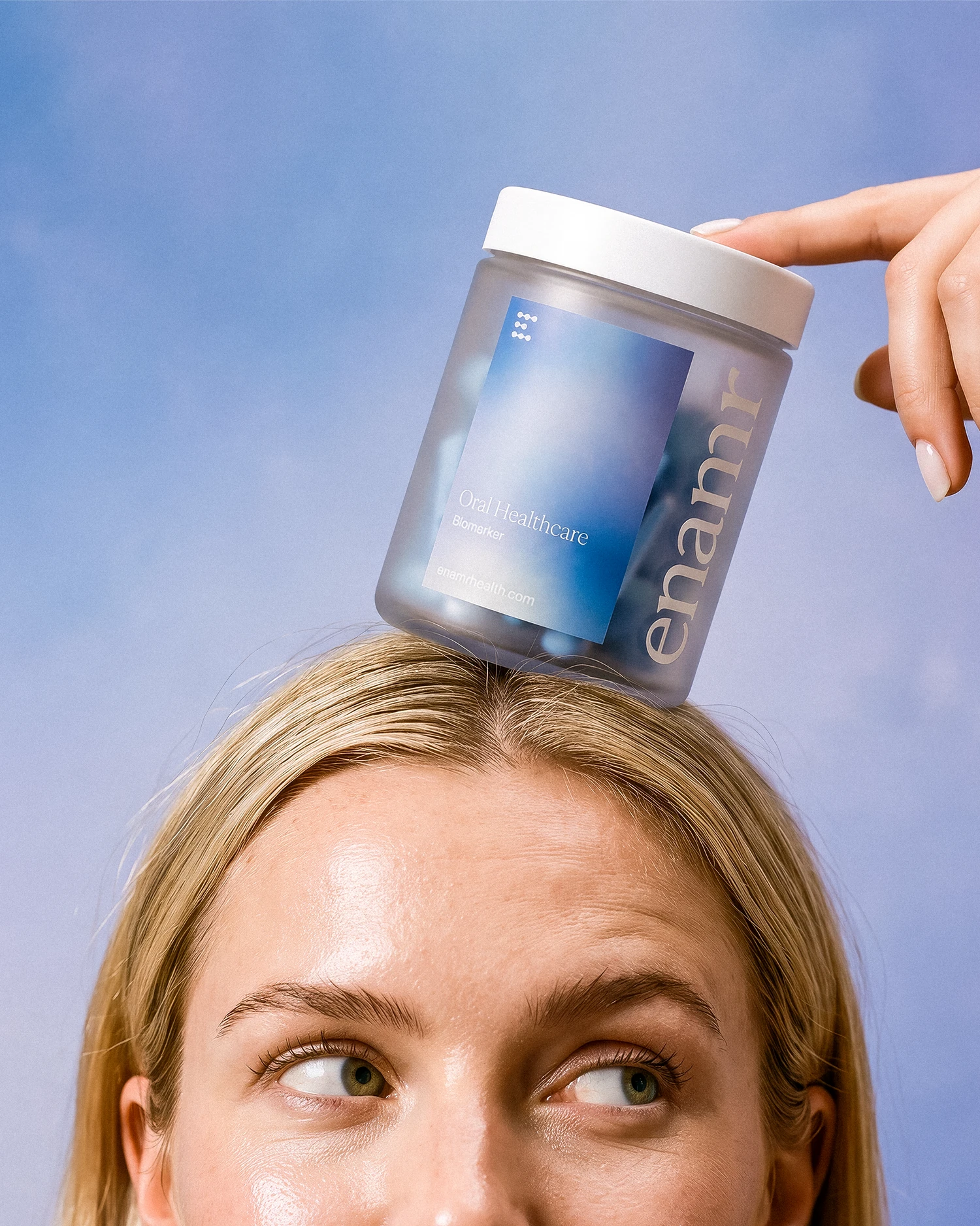 A woman balancing an Enamr oral testing kit jar on her head.